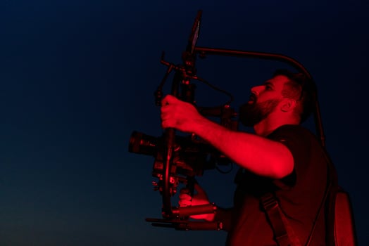 Nighttime Capture. Professional Videographer Films Athletes Running in Red-Lit Darkness photo