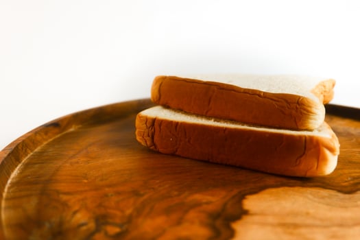 photography of white bread on a wooden coaster with a white background photo