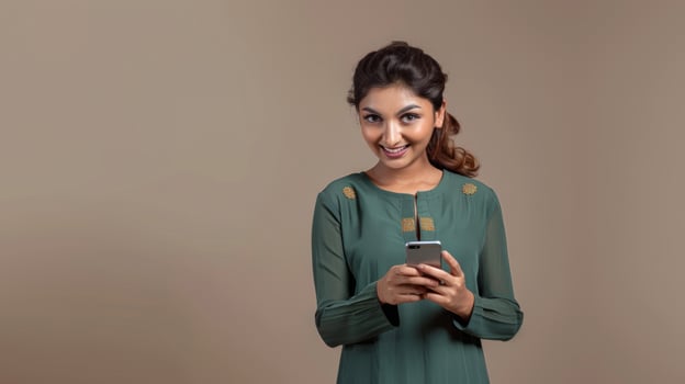 A young Indian woman looking at her phone on a plain background photo