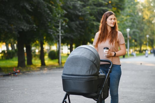 Mum walking on city street. Woman pushing her toddler sitting in a pram. Family concept. photo