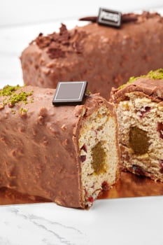 Sliced chocolate covered loaf cake with fruit jelly, dried cranberries and pistachio photo