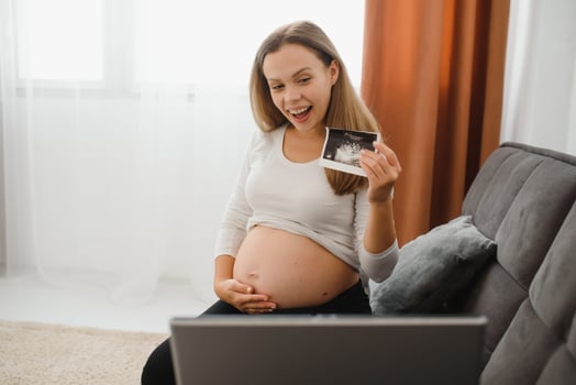 selective focus of cheerful pregnant woman showing ultrasound photos while having call