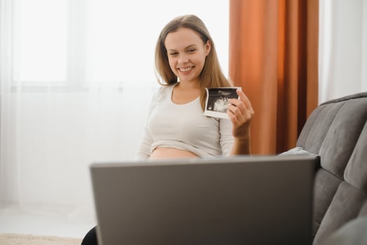 selective focus of cheerful pregnant woman showing ultrasound photos while having call