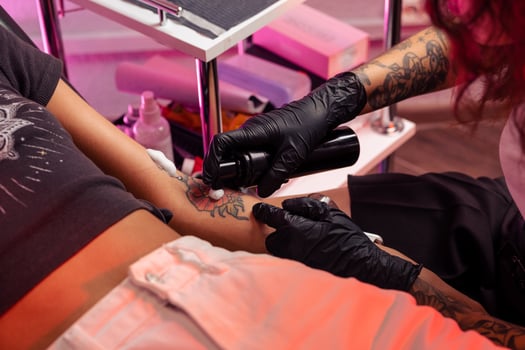 Professional tattoo artist applying antibacterial foam on tattooed skin photo