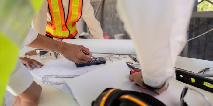 Engineer working on blueprint at construction site, detail of hands and tools. colleagues discussion concept photo