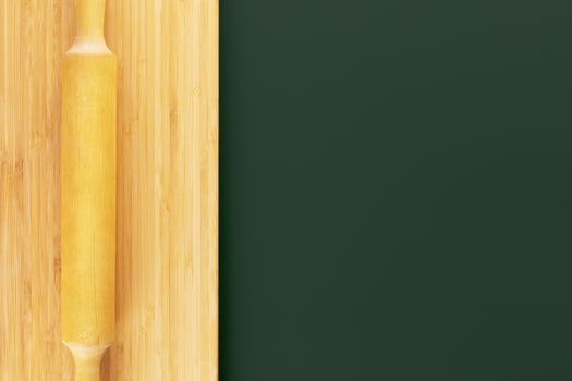 Wooden board with dough roller on a green background photo