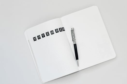Filling in the diary, writing November in a notebook in a dot photo