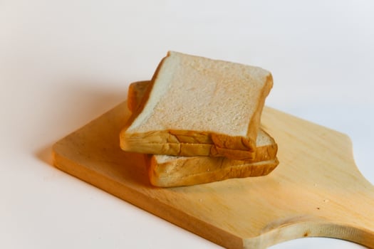 photography of bread on a wooden cutting board on a white background photo