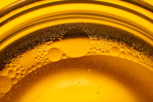 Yellow oil bubbles on water, cooking oil background. photo