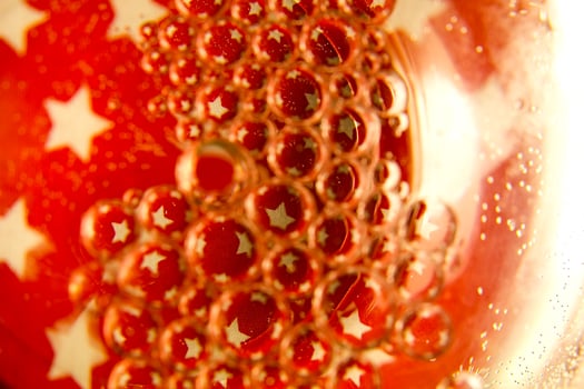 Red bubbles and drops of water on a white background star from an American flag. photo