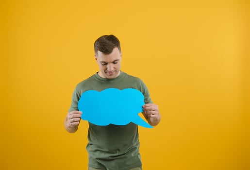 Cheerful young male pointing up and holding empty speech bubble with blank space for quote against vivid yellow background photo