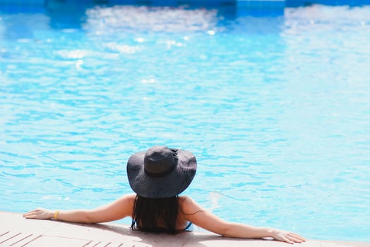 Vacation lifestyle scene of young woman sitting in swimming pool in morning time. Weekend and holiday lifestyle concept photo