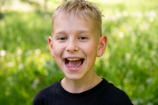 Portrait of a broadly smiling boy against a background of green grass. photo