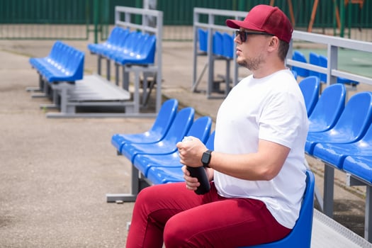 sportsman with a bottle of water sitting and resting at the seats at the stadium photo