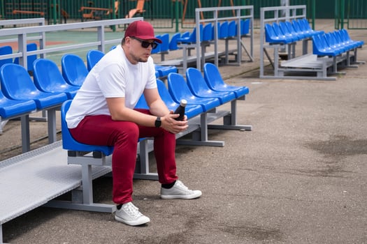 sportsman with a bottle of water sitting and resting at the seats at the stadium photo