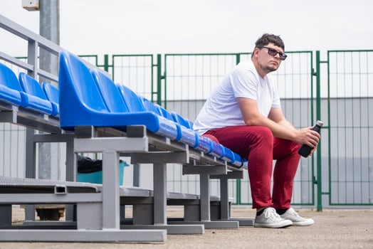 sportsman with a bottle of water sitting and resting at the seats at the stadium photo