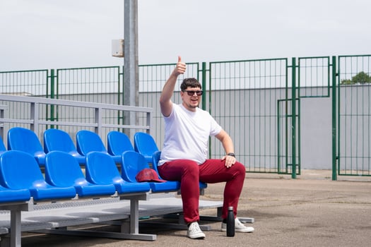 sportsman with a bottle of water sitting and resting at the seats at the stadium photo