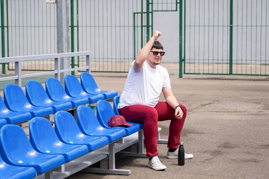 sportsman with a bottle of water sitting and resting at the seats at the stadium photo