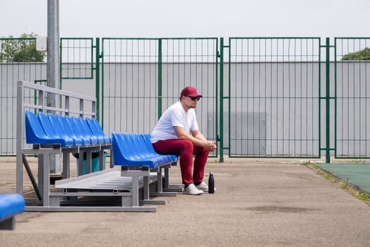sportsman with a bottle of water sitting and resting at the seats at the stadium photo
