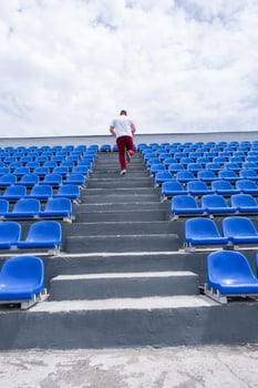 sportsman running in the stadium among blue seats photo
