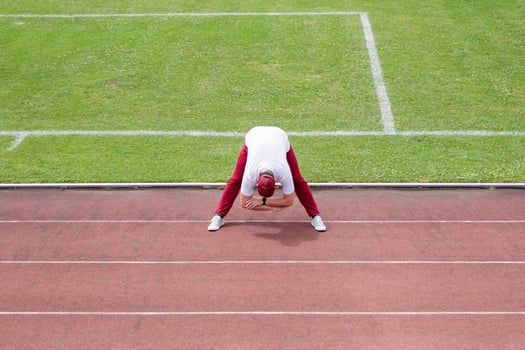 Athletic bearded man warms up before workout at the stadium photo