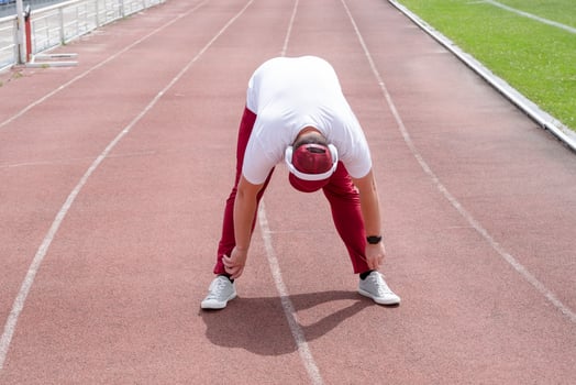 Athletic bearded man warms up before workout at the stadium photo