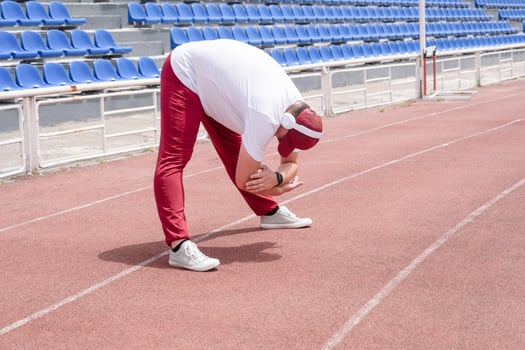 Athletic bearded man warms up before workout at the stadium photo