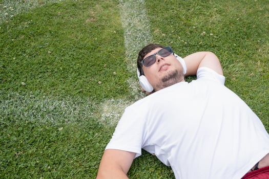 Athletic bearded man resting lying at grass at the stadium photo