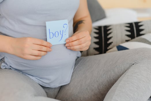 Pregnant woman with a sticky note and writing love boy or girl on sticky note and add on her belly,Pregnant Concept,Selective Focus photo