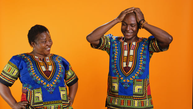 Joyful man and woman laughing together in studio, having fun with silly jokes over orange background. African american people enjoying funny moments with laugh, amused couple. photo