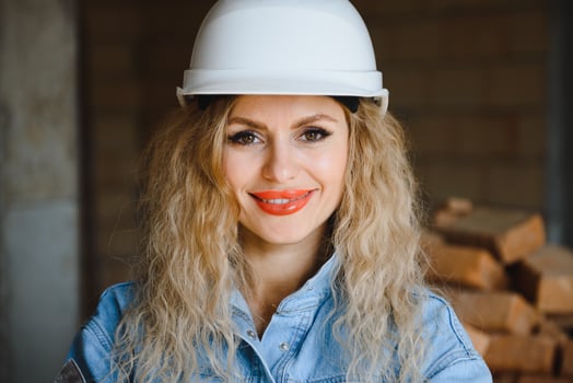 Construction concept. Pretty female builder in overalls and helmet working on construction site. photo