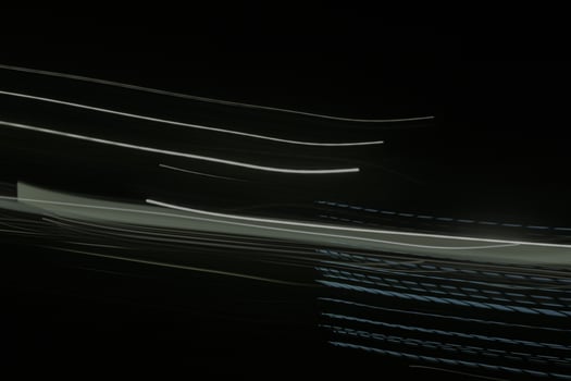 shows a long exposure photograph of light trails in the lamp. The trails are white and green, and they are streaking across the black background photo