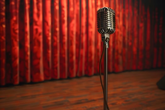 A close up of a microphone on a stand in front of a red curtain photo
