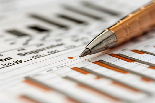 A pen resting on a finance document displaying a chart photo