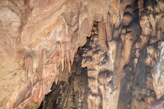 A cave with a lot of rock formations and stalactites hanging from the ceiling. Scene is mysterious and awe inspiring. photo