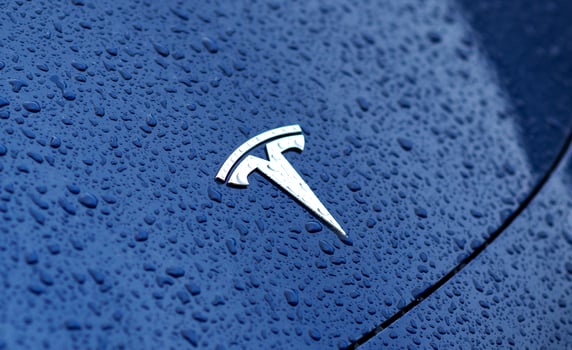 Kyiv, Ukraine. May 30, 2024. Tesla emblem in a close up view with water drops. Brand logo on a blue car hood photo
