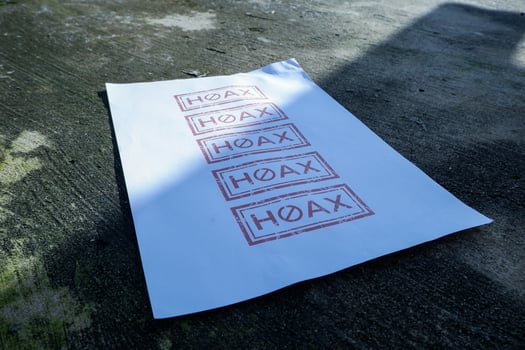 a piece of white paper on the floor with hoax written on it. illustration concept of stop giving false or fake news photo