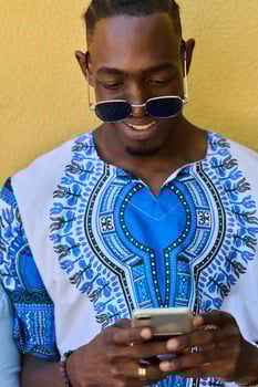 African American Teenager in Traditional Sudanese Attire Engaged with Smartphone photo