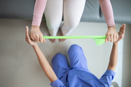 female doctor using elastic bands help patient regain muscle movement after recuperating from muscle injury and wants rehabilitate her be able use her normal daily life by practicing physical therapy photo