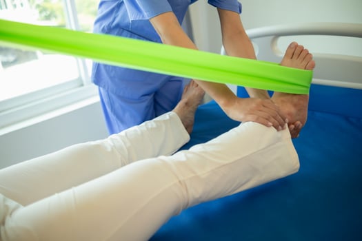 female doctor using elastic bands help patient regain muscle movement after recuperating from muscle injury and wants rehabilitate her be able use her normal daily life by practicing physical therapy photo