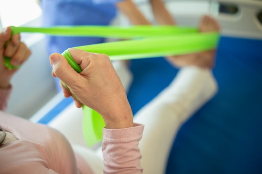 female doctor using elastic bands help patient regain muscle movement after recuperating from muscle injury and wants rehabilitate her be able use her normal daily life by practicing physical therapy photo