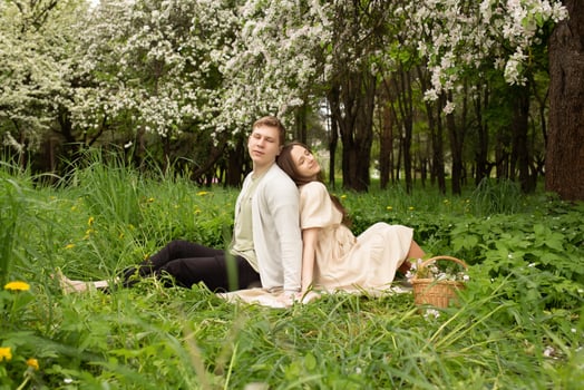 beautiful pregnant woman walks in a blooming garden. husband hugging pregnant wife on the picnic photo