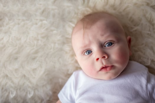 portrait of happy newborn baby boy lying on his back. beautiful newborn looks into the frame photo