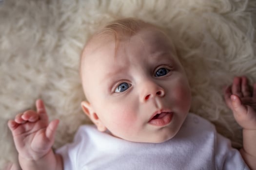 portrait of happy newborn baby boy lying on his back. beautiful newborn looks into the frame photo