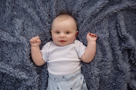 happy beautiful newborn baby boy lying on his back on a blue background. portrait beautiful newborn looks into the frame photo