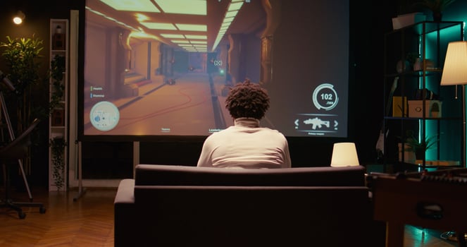 African american man plays first person shooter videogame on ultrawide smart TV with gun shooting at enemies. BIPOC gamer enjoying PvP online multiplayer game with players competing against each other photo