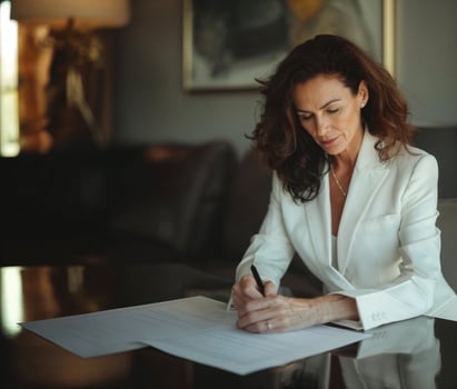 Elegant Middle Aged Woman Signing Document at Desk photo