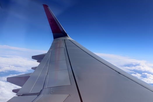 The wing of a jet plane and the scenery on the ground are visible through the porthole. photo