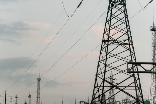 High voltage electric distribution network at sunset. Power transmission lines on supports with ceramic insulators and transformers at large electrical distribution substation photo