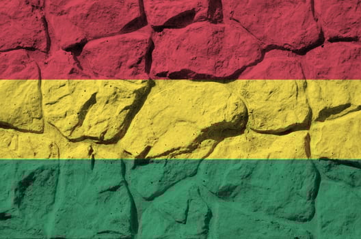 Bolivia flag depicted in paint colors on old stone wall closeup. Textured banner on rock wall background photo